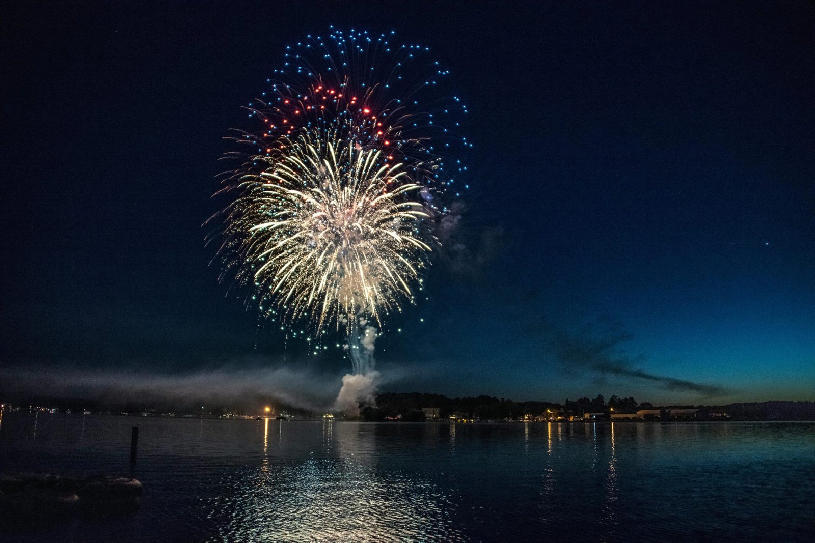 Vibrant fireworks illuminate the night sky over a serene lake, reflecting colors in East Berlin, PA.